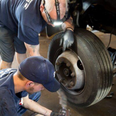 Two auto technicians working on a tire